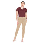 Woman wearing a maroon top and beige leggings on a white background