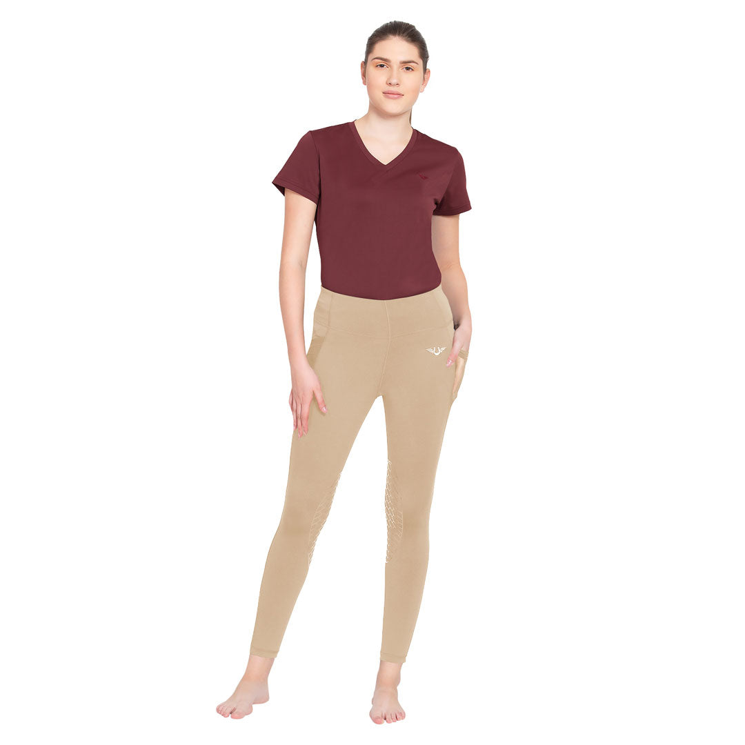 Woman wearing a maroon top and beige leggings on a white background