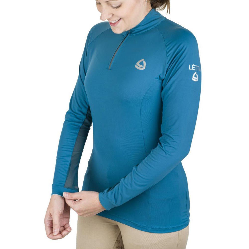 Woman wearing a blue long-sleeve athletic shirt with visible branding on a white background