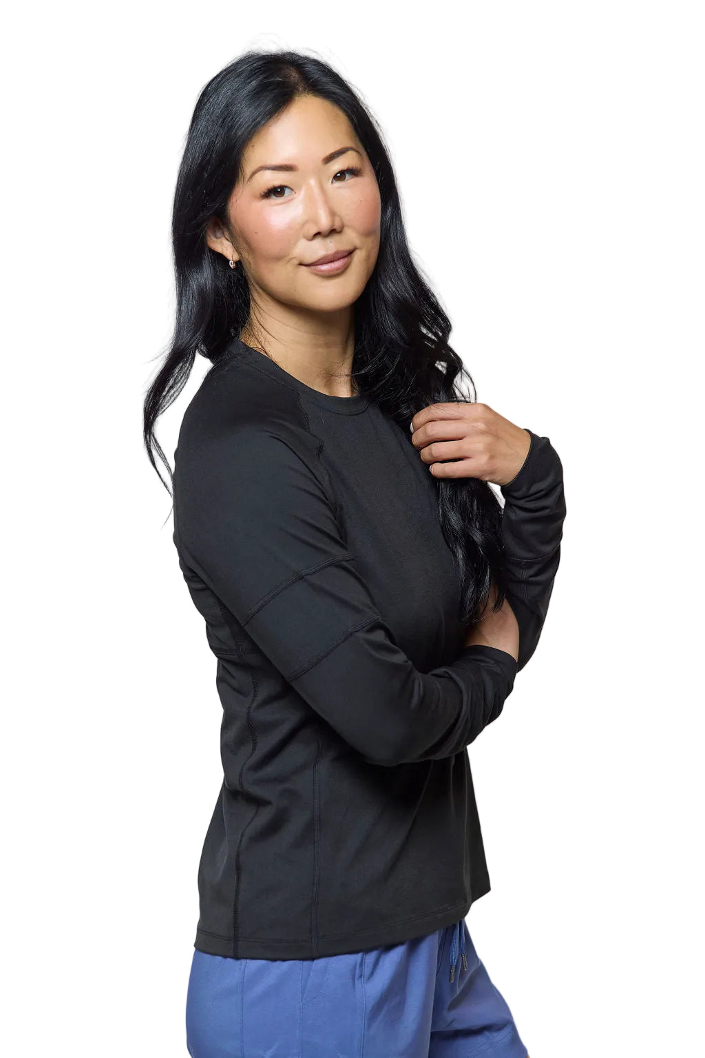 Woman wearing a black long-sleeve top and blue pants on a white background