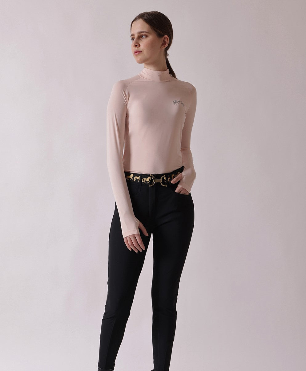 Woman wearing a light pink long-sleeve top and black pants on a plain background