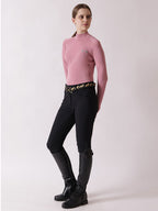 Person wearing a pink top and black riding pants with gold accents on a white background