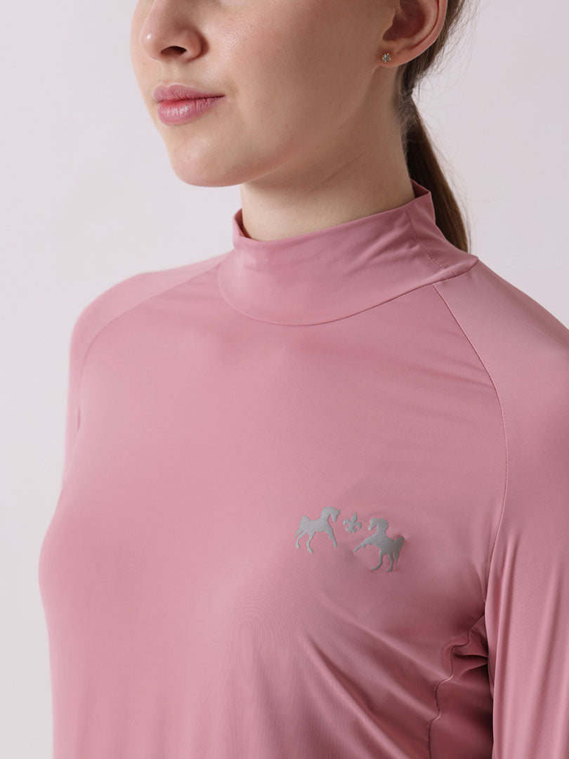 Close-up of a person wearing a pink high-neck top with a logo on a light gray background