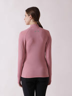 Woman wearing a pink long-sleeve athletic top on a light pink background