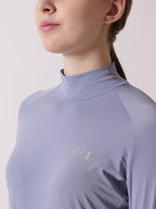 Person wearing a light purple long-sleeve shirt with a brand logo on a plain background