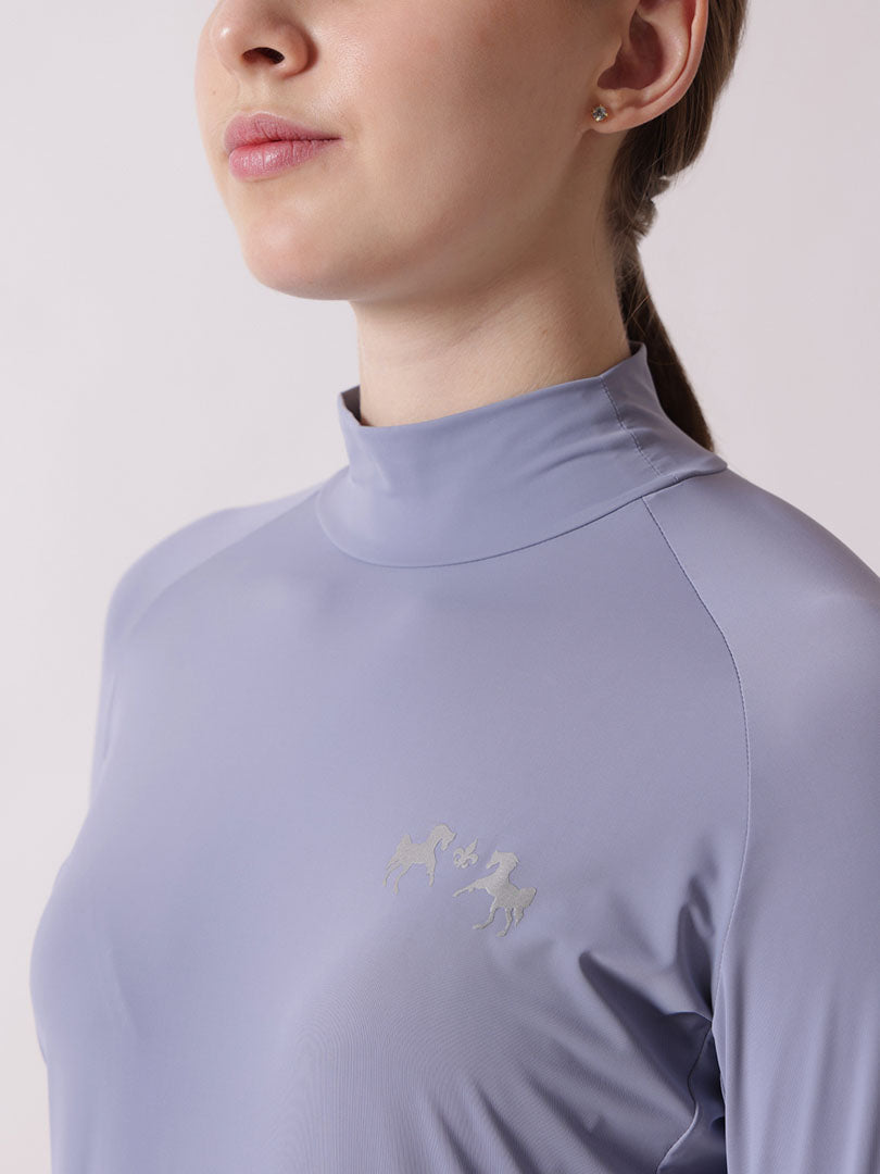 Person wearing a light purple long-sleeve shirt with a brand logo on a plain background