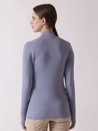 Woman wearing a light purple long-sleeve top on a plain background