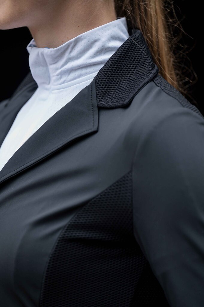 Close-up of a person wearing a dark gray equestrian jacket with a white shirt underneath.