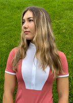 Person wearing a pink and white outfit against a grass background