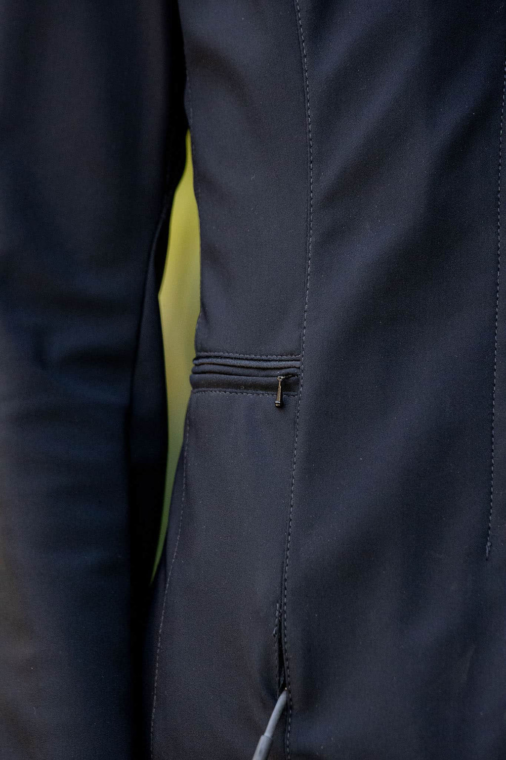 Close-up of a dark blue equestrian show jacket with a zipper detail