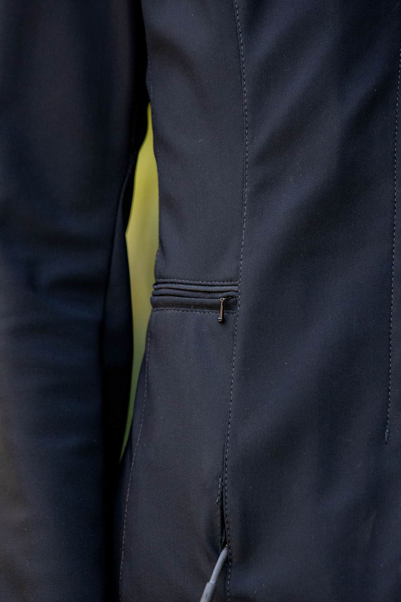 Close-up of a dark blue equestrian show jacket with a zipper detail