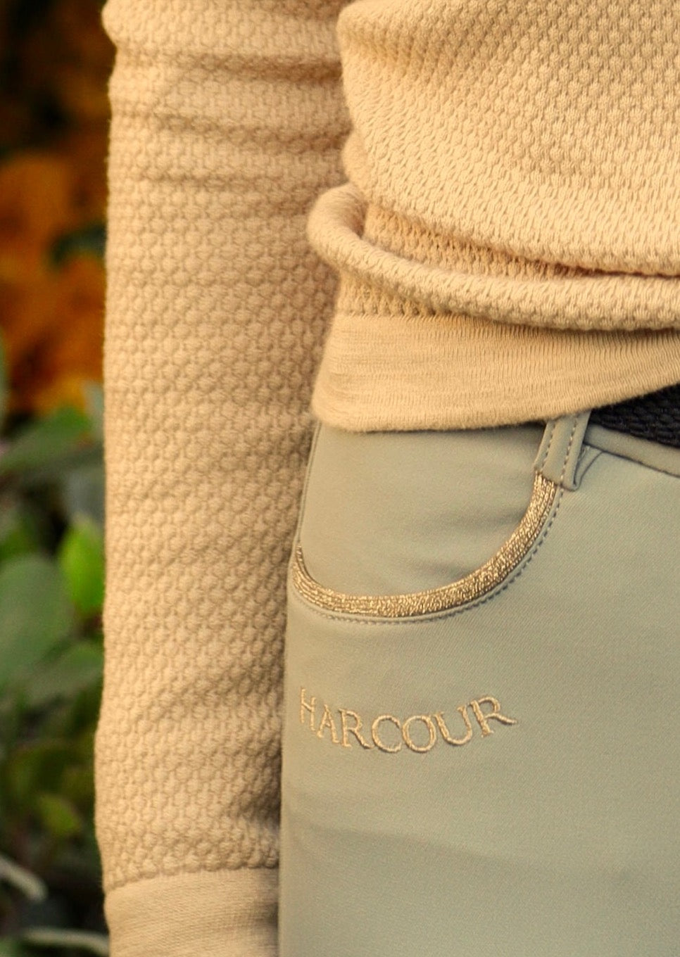 Close-up of beige fleece jacket and light beige riding pants with 'HARCOUR' branding.