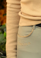 Close-up of beige fleece jacket and light beige riding pants with 'HARCOUR' branding.
