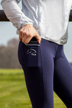 Person wearing navy riding pants with a visible brand logo, standing on grass.