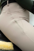 Close-up of beige riding pants with a zipper on a horse saddle.