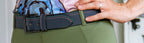 Person wearing a green belt with a colorful top and pink shirt.