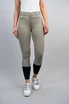 Person wearing beige riding pants with black socks on a gray background