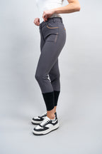 Person wearing gray riding pants with a white background