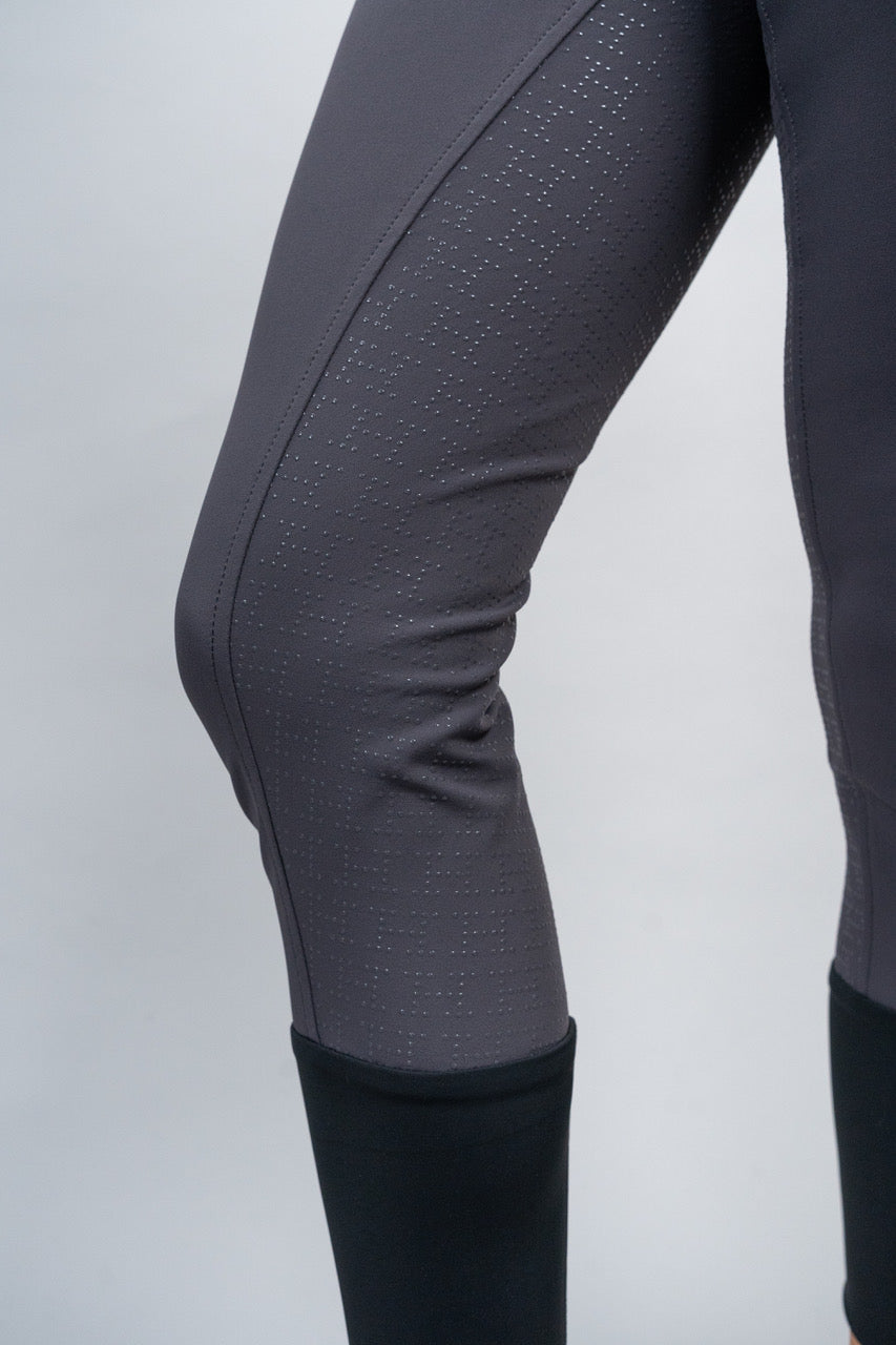 Close-up of gray riding pants with a textured grip pattern on a light gray background
