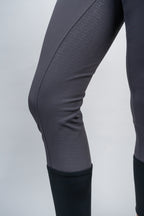 Close-up of gray riding pants with a textured grip pattern on a light gray background