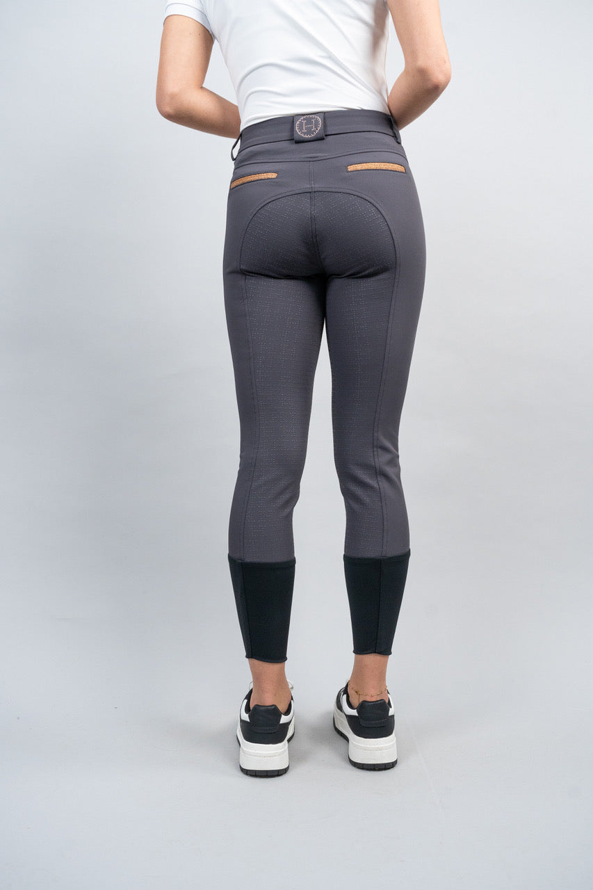 Person wearing gray riding pants with black socks on a light gray background
