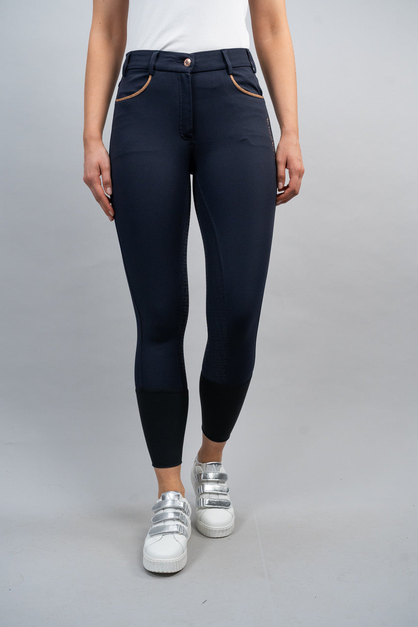 Person wearing navy blue riding leggings with white sneakers on a gray background
