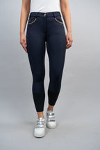 Person wearing navy blue riding leggings with white sneakers on a gray background