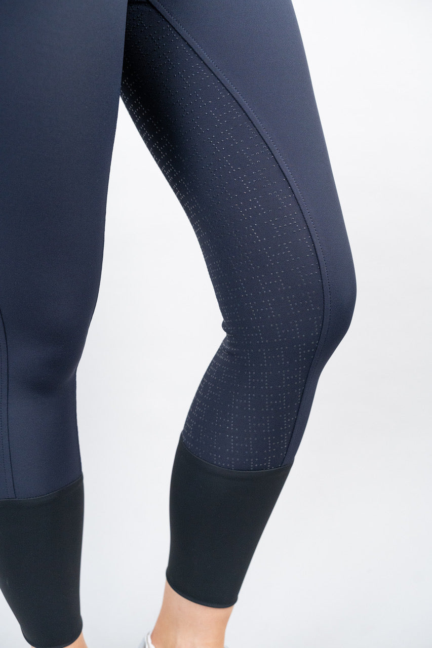 Navy blue equestrian leggings with patterned grip on the inner thigh on a white background