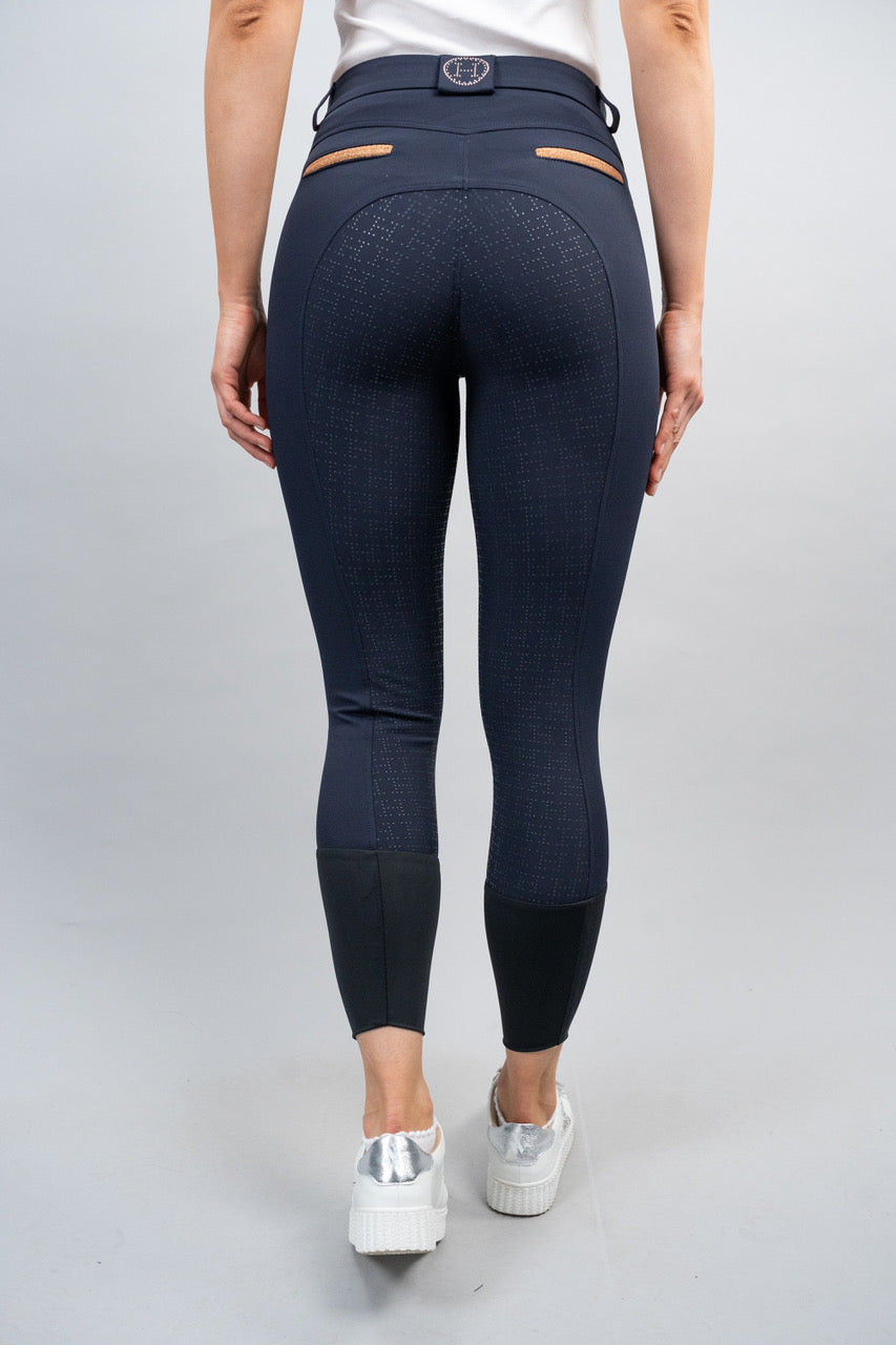 Person wearing navy blue riding pants on a plain background