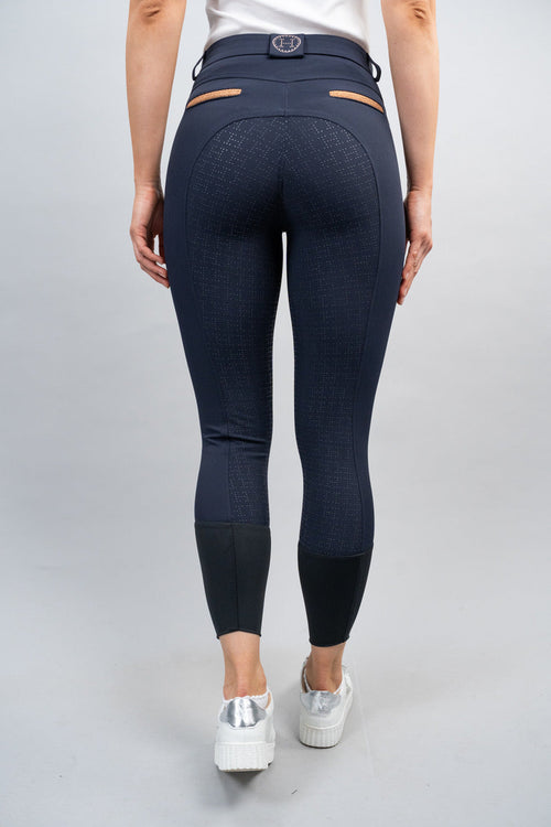 Person wearing navy blue riding pants on a plain background