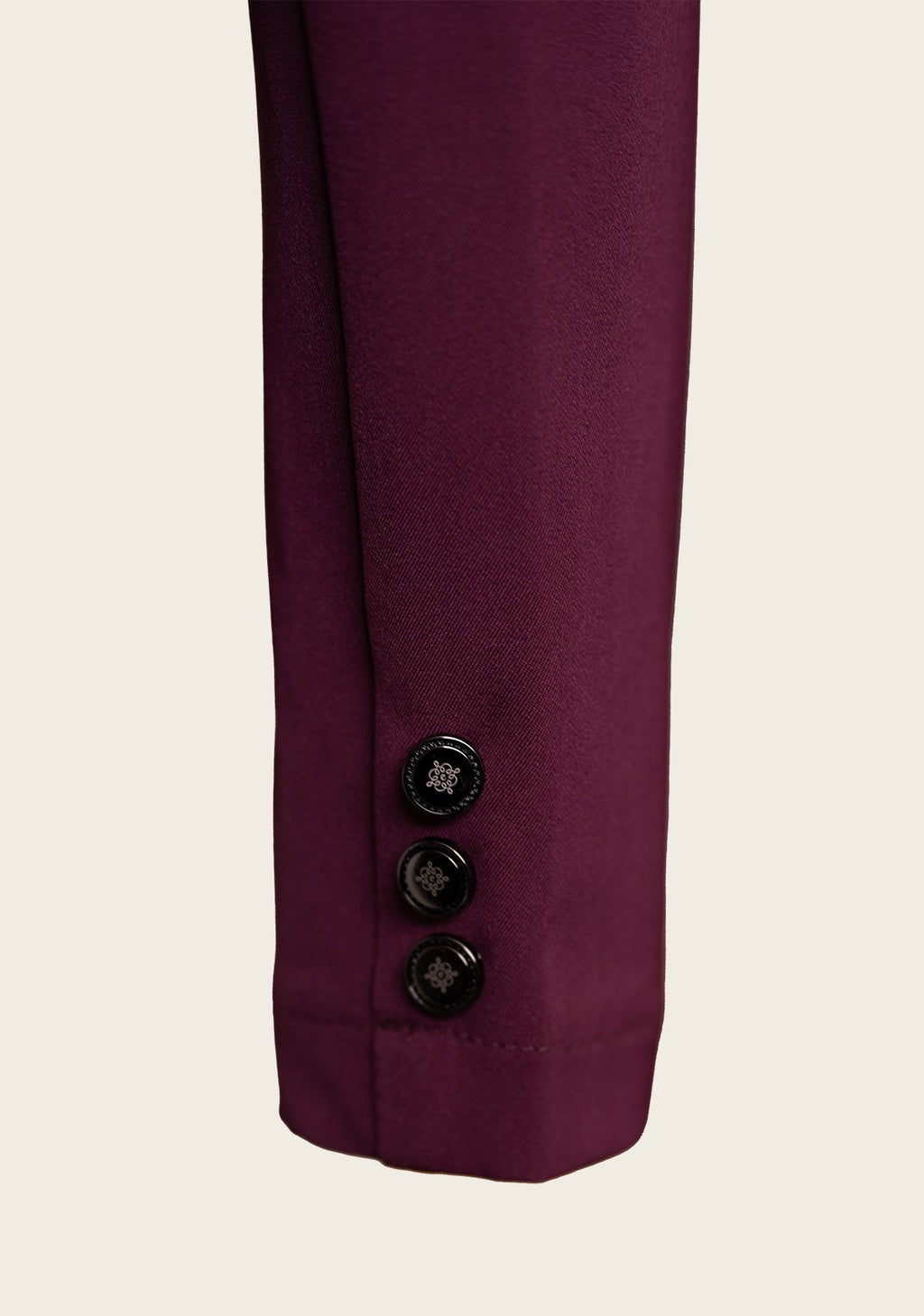 Close-up of a purple garment with three buttons on a light beige background