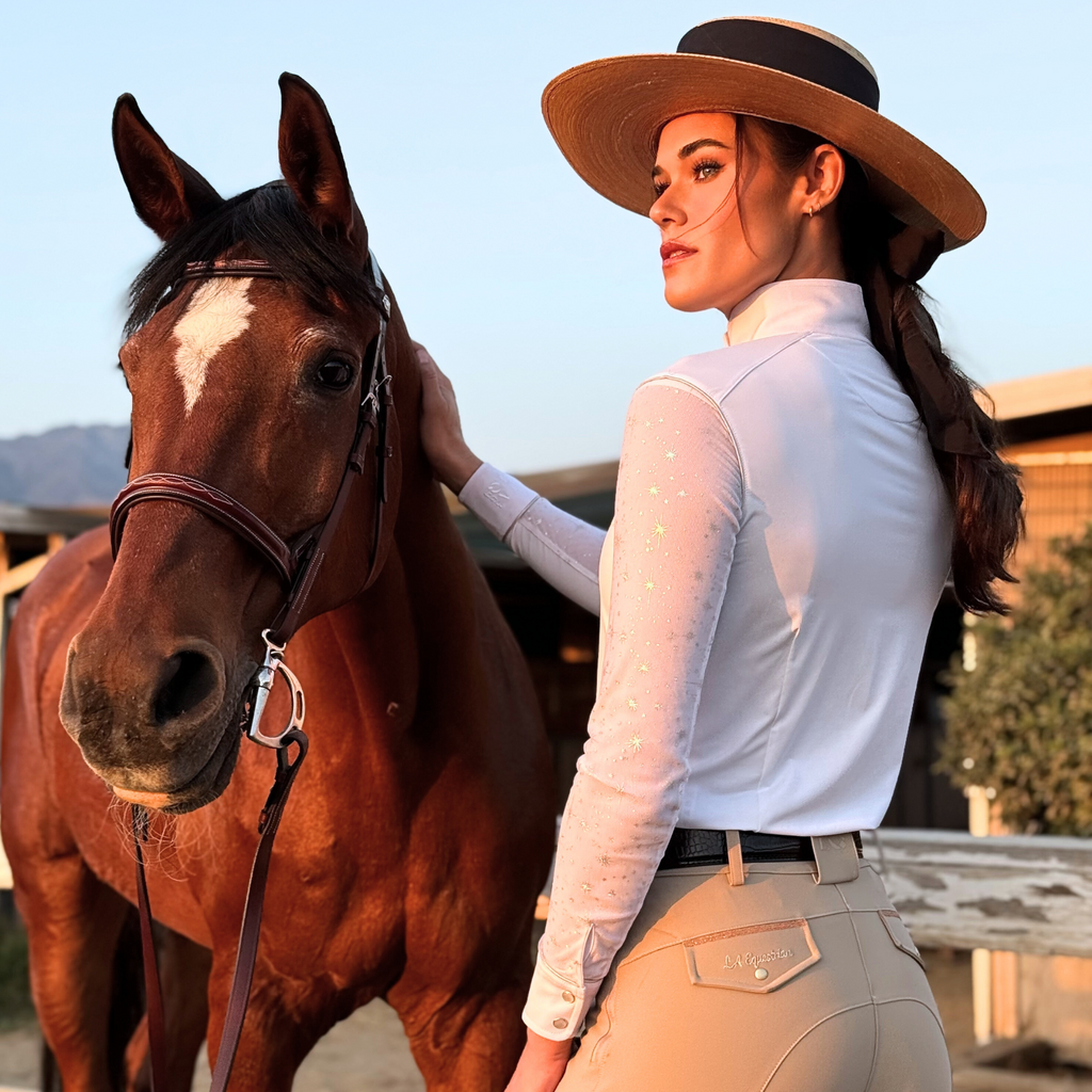 Woman in equestrian attire standing next to a horse outdoors