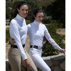 Two women wearing white long-sleeve shirts and beige riding pants standing outdoors.
