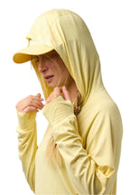 Person wearing a light yellow hoodie and cap on a white background