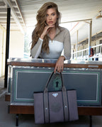 Woman holding a gray tote bag with a green emblem in an indoor setting