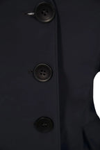 Close-up of a dark coat with button details on a plain background