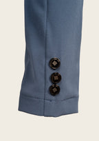 Close-up of a blue garment with three black buttons on a beige background