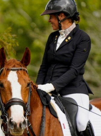 Person riding a horse in equestrian attire with a blurred natural background