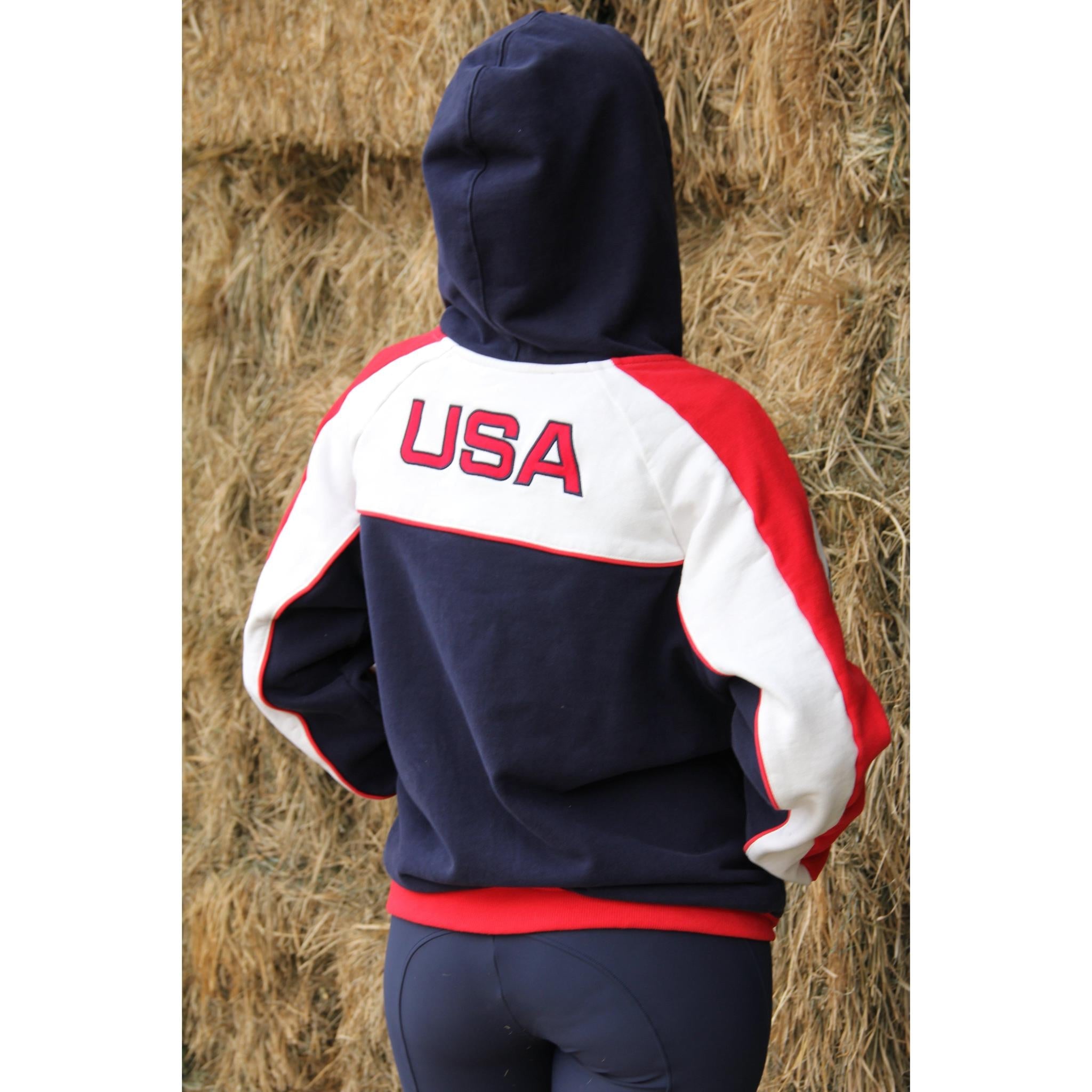 Person wearing a hoodie with 'USA' on the back, standing in front of hay bales.