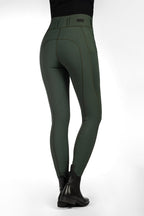 Green riding pants worn with black boots on a white background