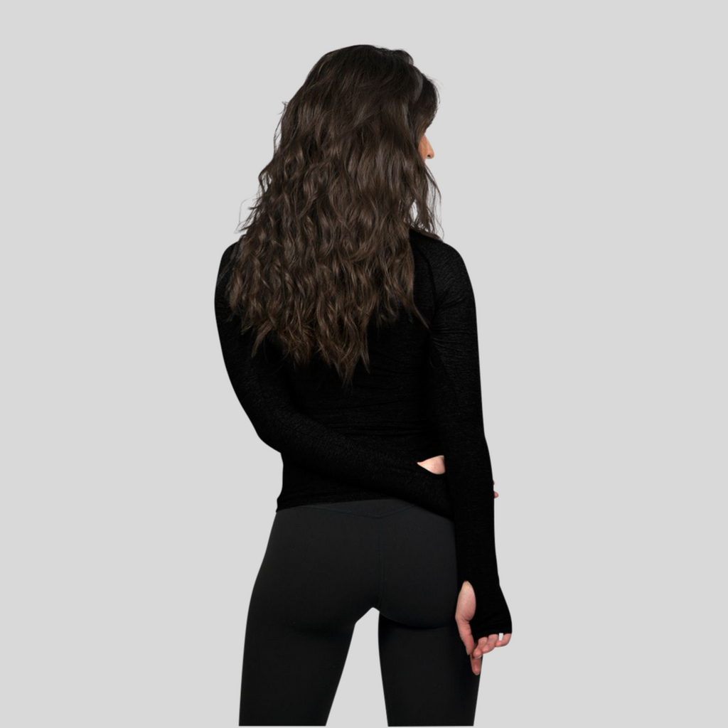 Person wearing a black long-sleeve top and black pants on a light gray background