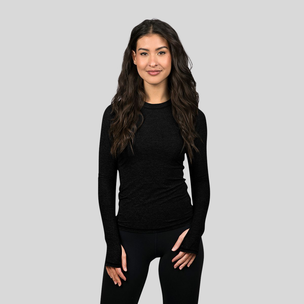 Woman wearing a black long-sleeve top and black leggings on a gray background