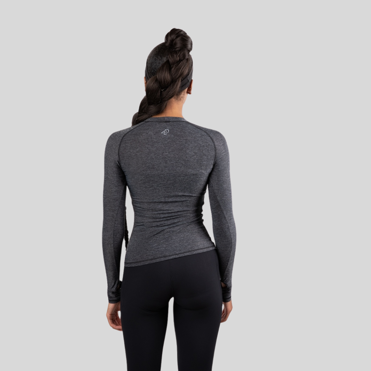 Person wearing a gray long-sleeve athletic top and black leggings on a light gray background