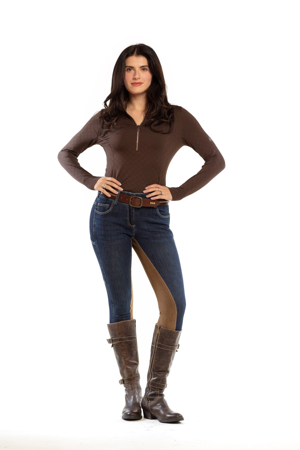 Woman wearing a brown long-sleeve top and blue jeans with brown accents on a white background