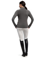 Person wearing a gray long-sleeve top and white pants with black riding boots on a white background