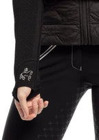 Close-up of a person wearing a black jacket and pants with a horse logo on the sleeve.