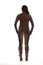 Person wearing a brown top and blue jeans with brown boots on a white background