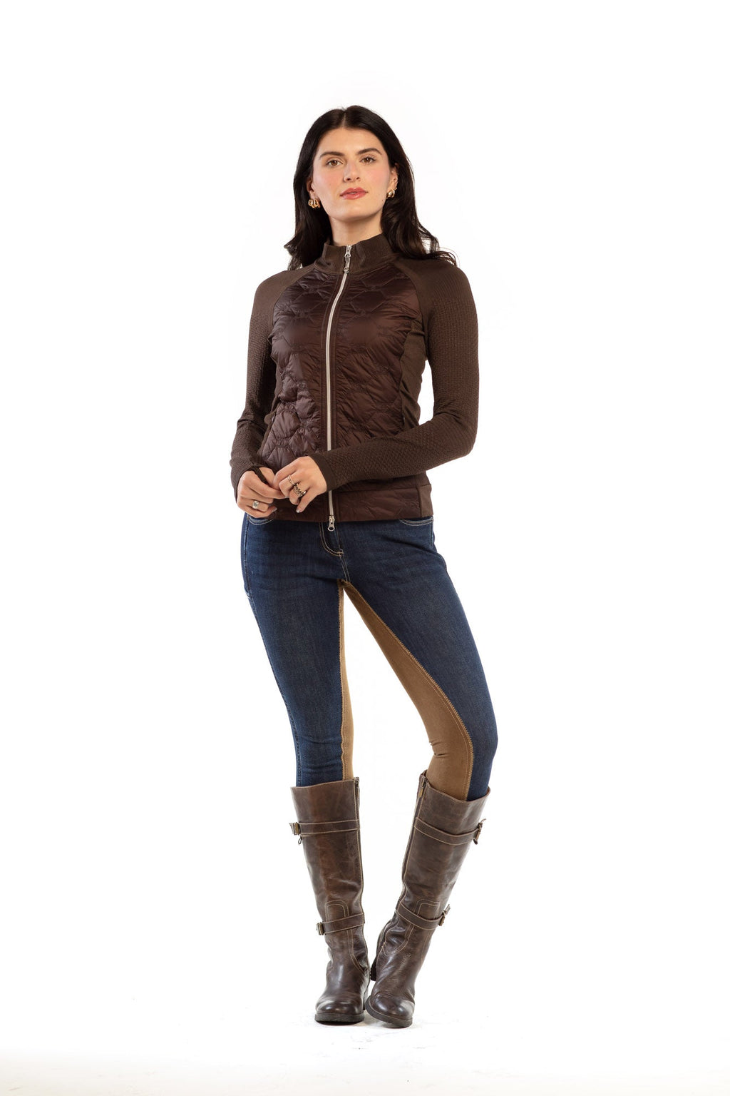 Woman wearing a brown jacket, blue pants with brown accents, and brown boots on a white background
