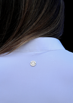 Close-up of a light blue shirt with a button, against a dark background
