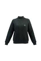 Woman wearing a black cable knit sweater with a logo on a gray background